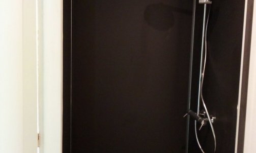 Douche à l'italienne avec panneaux muraux et bac couleur noir et colonne de douche avec pomme de douche